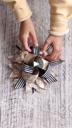 a person is tying a ribbon around a decorative object on the floor with their hands