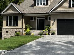 a house with two garages in front of it and landscaping around the driveway area