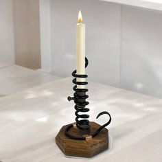 a white candle is sitting on top of a wooden stand with black spirals around it