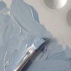 a paintbrush is sitting on top of a blue painted piece of art paper that looks like it has been dipped with white acrylic