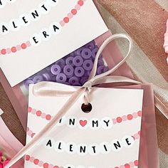 two valentine's day tags tied to pink and purple paper with the words i love my valentine written on them