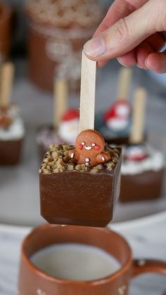 a person holding a stick with some food on top of it next to a cup of coffee