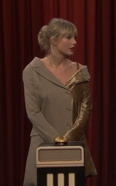 a woman in a dress and gloves standing at a podium with an award on it