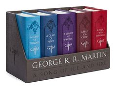 the game of thrones book set is in a wooden holder with four different colors