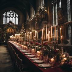 a long table with candles and flowers on it in front of a large church window