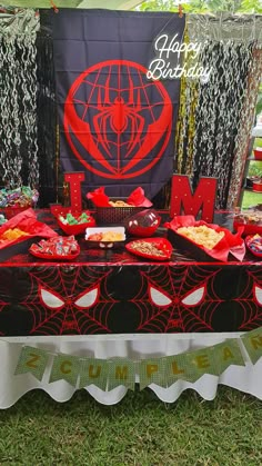 a table topped with lots of food on top of a grass covered field next to a sign