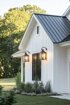 a white house with black roof and two lights