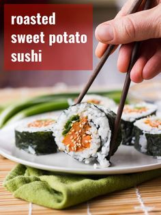 someone is holding chopsticks to some sushi on a white plate with green beans