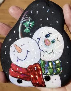 a hand painted rock with two snowmen on it