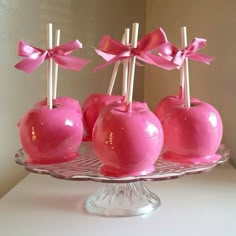 some pink apples are sitting on a glass platter with toothpicks in them