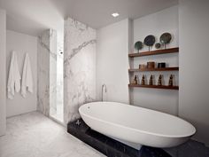 a white bath tub sitting in a bathroom next to a shelf with towels on it