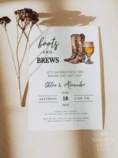 a wedding card with boots and a glass of wine next to it on a table