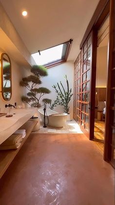 a large bathroom with a skylight above the bathtub and trees on the wall