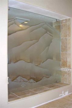 a bathroom with a glass shower door and tiled walls in the background is a desert scene