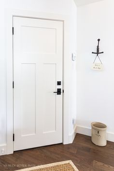 a white door in the corner of a room with a basket on the floor next to it