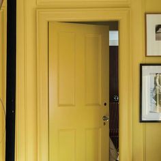 an open yellow door in a room with pictures on the wall and carpeted floor