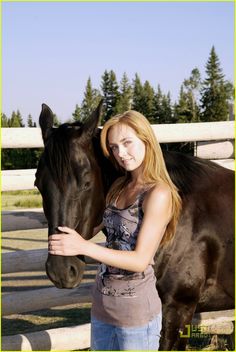 a beautiful young woman standing next to a brown horse