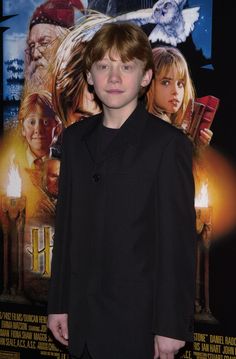 a young boy standing in front of a movie poster