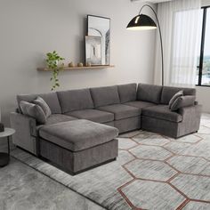 a living room with a large sectional couch and ottoman in front of a big window