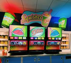 three televisions sitting next to each other in front of a display case with drinks on it