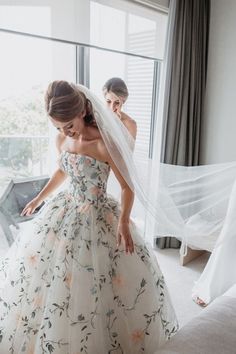 a woman in a wedding dress looking down at the floor with her veil over her head