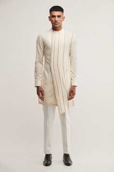 Vanilla asymmetric kurta with stripe embroidery and mandarin collar. Paired with pant cut style pyjama.
Component: 2
Pattern: Embroidered
Type Of Work: Striped
Neckline: Mandarin
Sleeve Type: Cuff Sleeves
Fabric: Handloom Cotton
Color: Beige
Other Details: 
Striped panel
Occasion: Puja - Aza Fashions Indowestern Outfits For Men, Kurta Designs Men's, Men Aesthetic Outfits, Layered Kurta, Cotton Kurta Set, Wedding Kurta For Men, Gents Kurta, Kurta Patterns, Kurta Set For Men