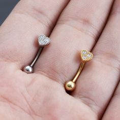 a person is holding two different types of piercings in their hand, one with a heart and the other with a diamond