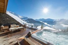 a hot tub sitting on top of a wooden deck next to a snow covered mountain