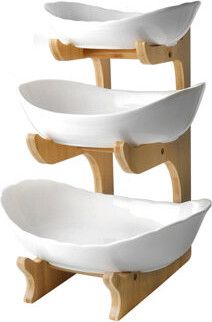 three white bowls are stacked on wooden stands