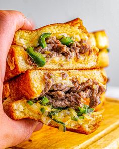 a person holding up a sandwich with meat and vegetables