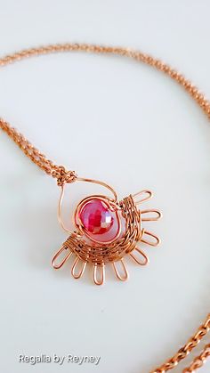 a gold necklace with a red stone in the center