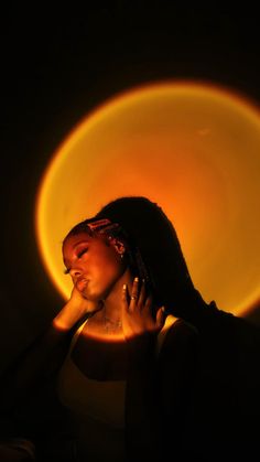 a woman with her hands on her face in front of a circular light that is shining brightly