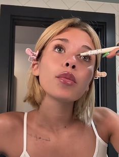 a woman is brushing her teeth in front of a mirror with an electric toothbrush