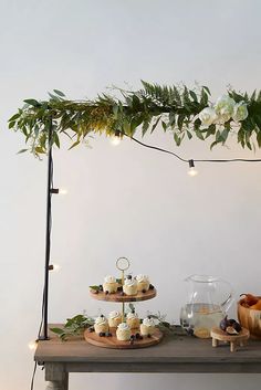 a table topped with cupcakes covered in frosted icing and greenery