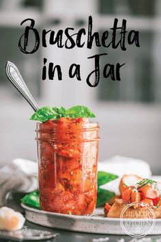 a glass jar filled with tomatoes and basil on top of a plate next to a spoon