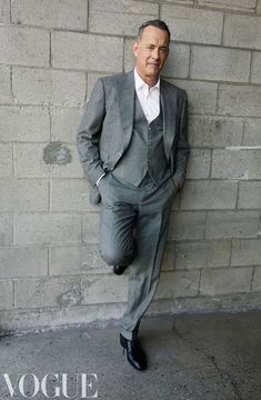 a man in a suit leaning against a brick wall