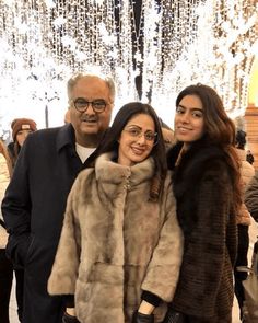 two people standing next to each other in front of a chandelier filled with lights