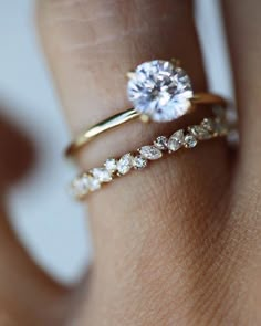 a woman's hand with two gold rings and a diamond ring on her finger