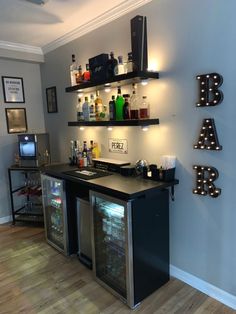 a bar with lighted letters and liquor bottles on the shelves above it, along with other items