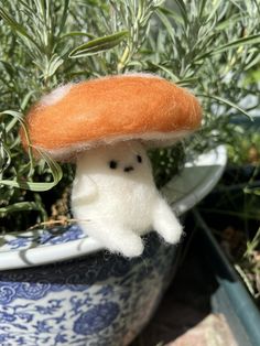 an orange mushroom sitting on top of a blue and white planter next to green plants