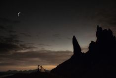 two people standing on top of a mountain at night