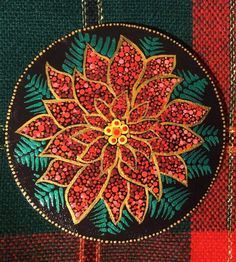 an embroidered poinsettia on a green and red checkered cloth with gold trim