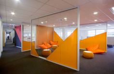 an office cubicle with orange and pink walls, bean chairs and round ottomans