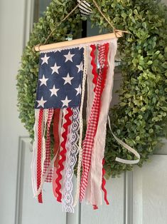 an american flag is hanging on the front door with ribbons and laces around it