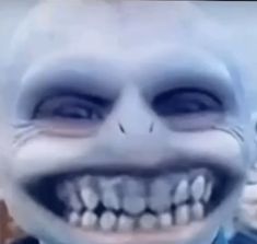 a creepy looking man with white teeth wearing a blue shirt