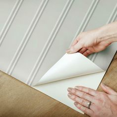 two hands are holding an envelope over a piece of paper that is folded in half