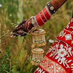 a woman in a red and white dress is holding some gold jewelry on her hand