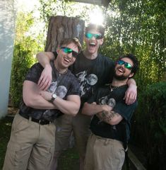 three men in sunglasses are posing for the camera with their arms wrapped around each other