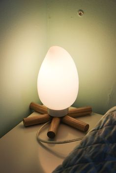 a white light sitting on top of a wooden table next to a lamp shade and pillows