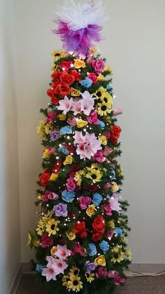 a decorated christmas tree with colorful flowers on the top and lights in the bottom half